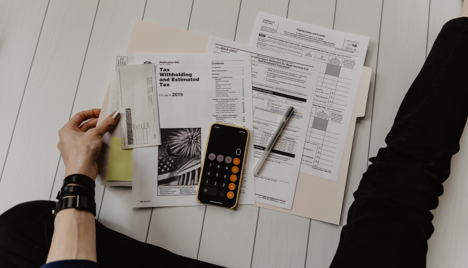Hands at a desk reviewing spreadsheets and a building inspection report